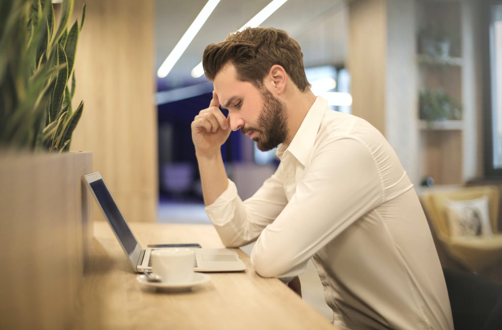 Man denkt na terwijl hij kijkt naar laptop.